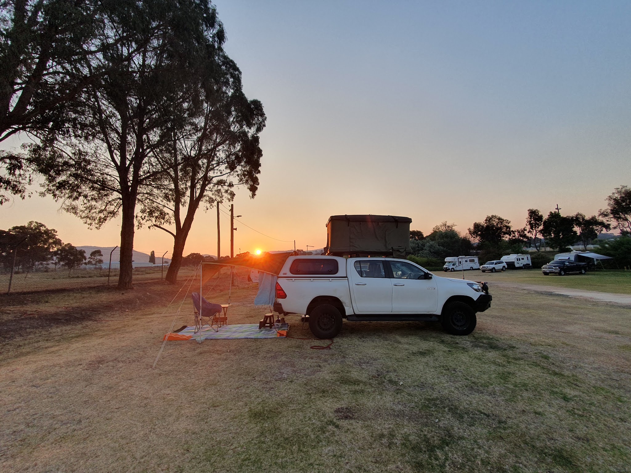 A 4WD with a rooftop tent and awning set up at sunset at the showground